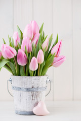 Spring easter tulips in bucket on white vintage background.