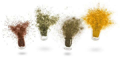 glass jars with various spices flying on white background