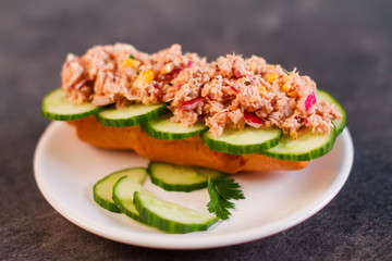 Sandwich with tuna and vegetables on rye bread on wood background