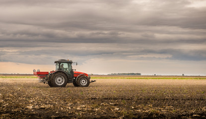 Obraz premium Farmer with tractor seeding - sowing crops at agricultural fields