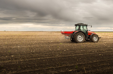Obraz premium Farmer with tractor seeding - sowing crops at agricultural fields
