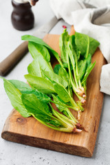 Fresh raw spinach leaves on a wooden rustic stand on a gray old concrete background. Ingredients for salad. Selective focus. Top view. Copy space.