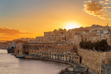 Naklejka premium Zachodzący zachód słońca nad pięknym miastem Valletta, stolicy Malty, znanym w języku maltańskim jako Il-Belt, malownicze i kolorowe miasto.