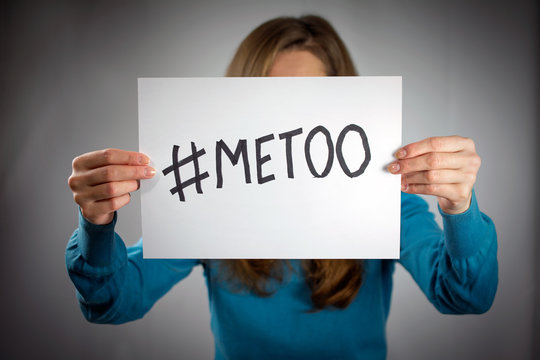 a young woman holds a banner with the inscription "#metoo" in front of her. Blue sweater, long hair. Me Too movement. selective focus , blurred neutral background, vignetting