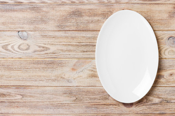 Top view of empty white food plate on a wood background