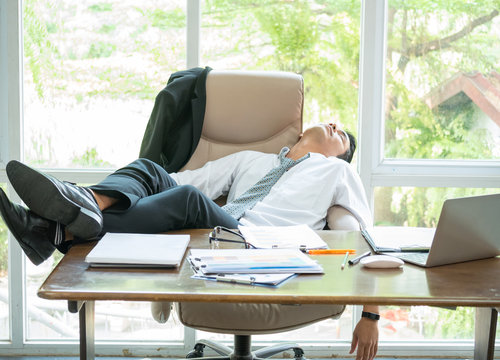 Tired businessman sleeping in the office with his feet up on the desk