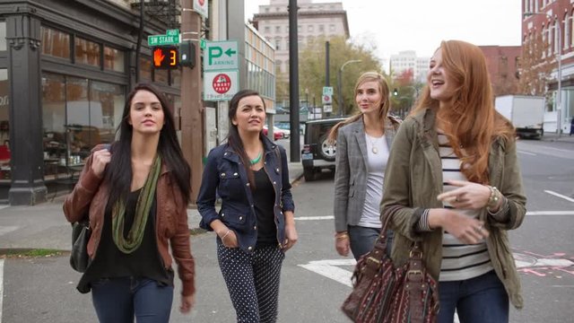 Handheld shot of female friends crossing road in city