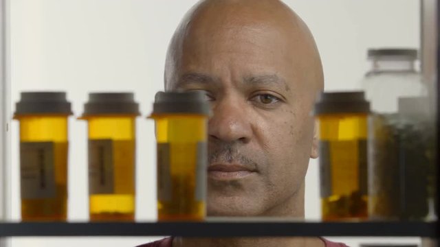 Man taking bottle of pills  from medicine cabinet