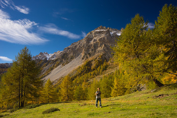 Fototapeta na wymiar Hiker walking on a colorful valley with great panoramic view and vivid colors. Wide angle shot in the Italian French Alps.