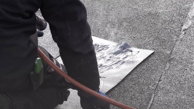 Roofer installing chimney using bitumen and gas flame