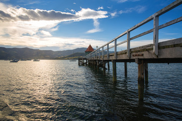 Obraz premium Sunset view of wooden pier in Akaroa bay, near Christchurch, New Zealand 