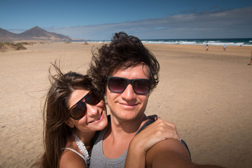 Happy embracing young couple portrait at the beach. Medium close-up. Fuerteventura, Canary islands, Spain.