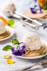 Vanilla ice cream scoop with edible flowers pansy. Summer food concept.