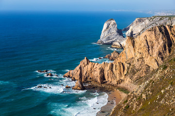Fototapeta na wymiar Ocean meets Cliffs of Cabo da Roca (Cape Roca) in Sintra - the westernmost extent of mainland Portugal and Europe. The most western point of Europe. Popular touristic destination and attraction.
