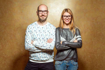 fashion hipster couple in love in glasses posing on a gold background. The concept of St. Valentine's Day..