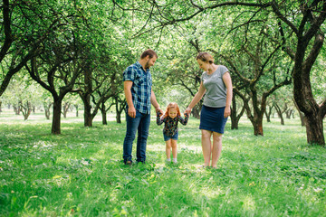 Obraz premium Cute young happy family having fun in the park. Little girl with parents outdoors. Mother father and daughter.