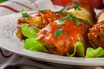Stuffed cabbage with meat and rice served with boiled potatoes and tomato sauce