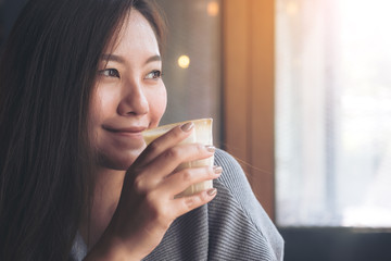 Closeup image of Asian woman smelling and drinking hot coffee with feeling good in cafe