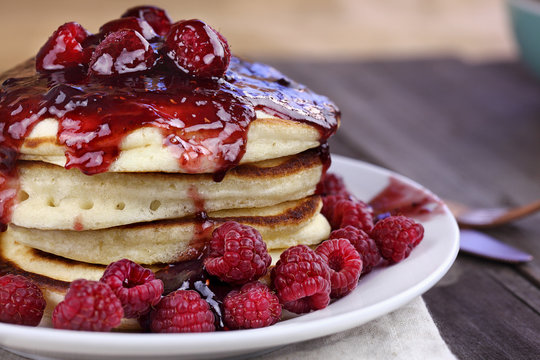 Delicious homemade golden pancakes with fresh raspberries, and raspberry syrup. Extreme shallow depth of field.