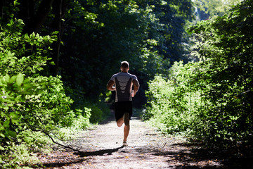 Sports man making a run down the track in the woods.
