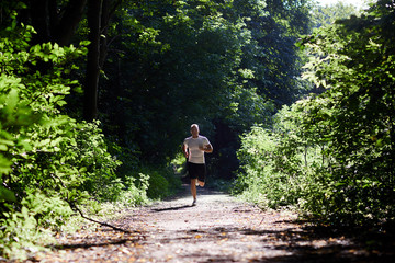 Sports man doing Jogging in sportswear along the path in the woods.