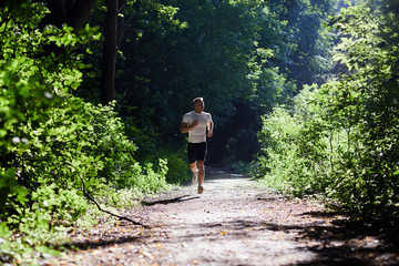 Sports man doing Jogging in the Park on the track in the morning at dawn.