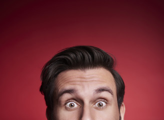 Part of terrified man peeking at studio shot