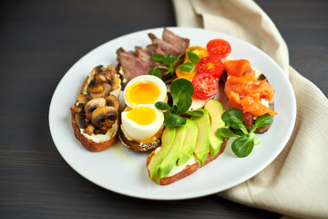 Bruschetta, assorted, different fillings, on plates with a soft-boiled egg in the middle