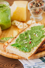 Bruschetta with basil walnut pesto sauce on a wooden plate. Wooden backdrop.