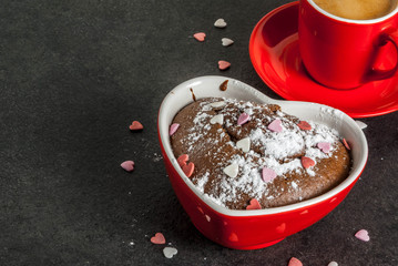 Valentine's day background, red coffee mug and chocolate mug cake or brownie with powdered sugar and sweet heart shaped sprinkles, black background, copy space