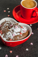 Valentine's day background, red coffee mug and chocolate mug cake or brownie with powdered sugar and sweet heart shaped sprinkles, black background, copy space