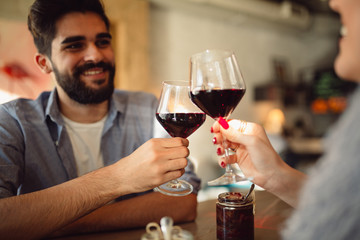 Couple clinking glasses with red wine. Couple celebrating anniversary or Valentine's day.