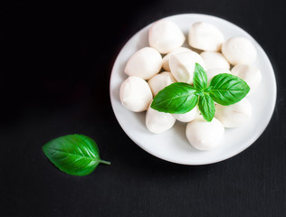 Fresh cherry tomatoes, basil leaf, mozzarella cheese on black slate stone chalkboard with copyspace. Healthy Italian traditional caprese salad ingredients. Organic Mediterranean food concept, flat lay