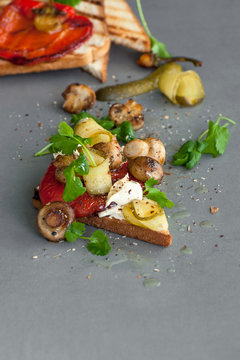 Toast with mild cheese, pepper grilled and fried paddles on a gray stone background..