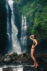Young sexy woman looking at the waterfall in jungles. Ecotourism