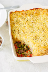 Shepherds pie -  Irish traditional food. Served in a ceramic dish on a white stone background.