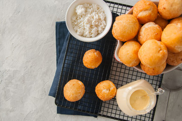 Small cottage cheese doughnuts (castgnole) served on a wire rack. White stone background.