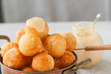Small cottage cheese doughnuts (castgnole) in a bowl. White stone background.