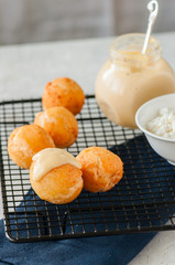Small cottage cheese doughnuts (castgnole) served on a wire rack. White stone background.