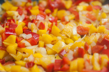 poivrons rouge et jaune coupés en dés dans une poêle 