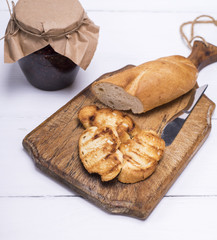 Naklejka premium pieces of white bread on a brown wooden board and raspberry jam