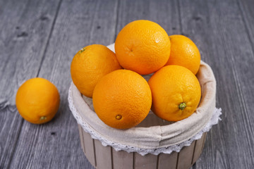 Basket of oranges on wooden background.