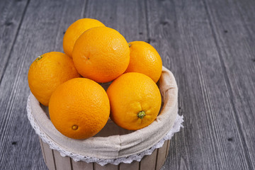 Basket of oranges on wooden background.