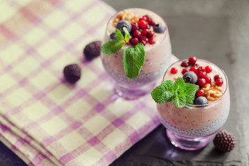Layered chia, banana and berry smoothie garnished with fresh  mint, healthy food style on black slate background