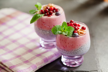 Layered chia, banana and berry smoothie garnished with fresh  mint, healthy food style on black slate background