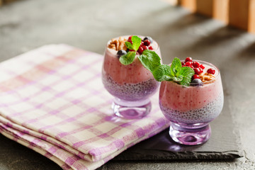 Layered chia, banana and berry smoothie garnished with fresh  mint, healthy food style on black slate background