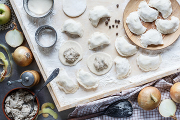 The process of making homemade traditional dumplings.  Cutting and stuffing dumplings. Pierogi, pelmieni, ravioli. Onions, meat, four, pepper, mould. Top view.