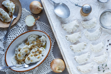 Dumplings raw on a wooden board. Traditional homemade food. Traditional pierogi, pelmeni, ravioli,...