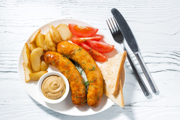 fried sausages with potatoes and mustard on white table, top view