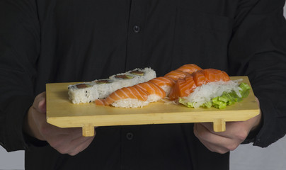 Cocinero de comida Japonesa sujeta plato con sushi